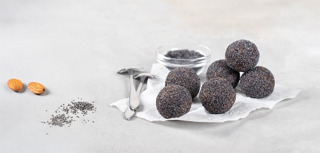 Makové guličky, obalené v maku na bielom stole - vianočné pečenie