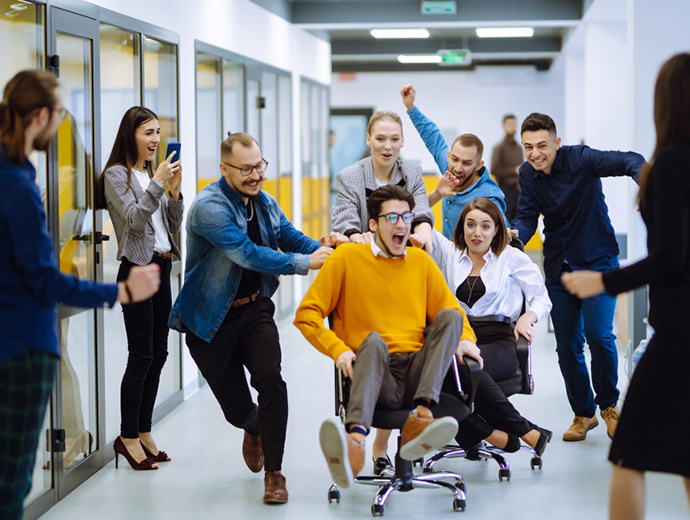 Skupina zamestnancov sa zabáva na teambuildingovej súťaži v kancelárii.